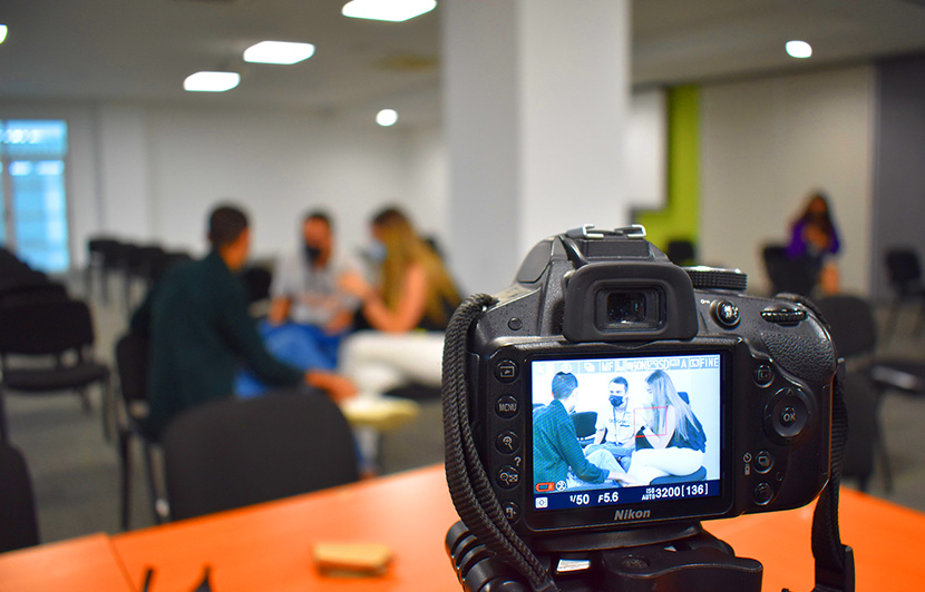 cámara capturando entrevista para proyecto de comunicación social en sala de reuniones