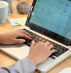 persona trabajando en un computador portátil con un calendario abierto en la pantalla