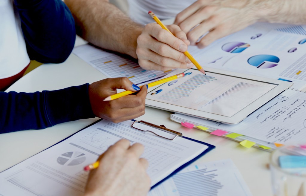 mesa de trabajo con informes, gráficos y herramientas digitales para análisis administrativo