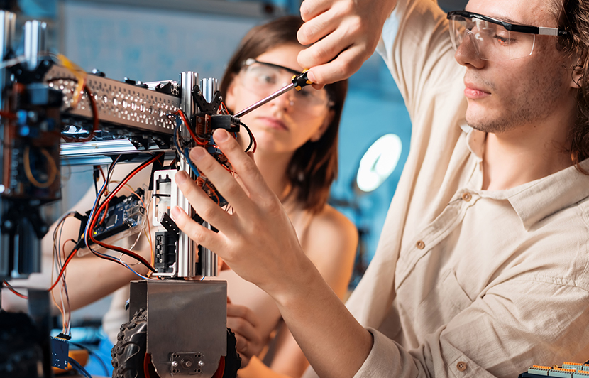 estudiantes de ingeniería mecánica trabajando ensamblaje de prototipo robótico