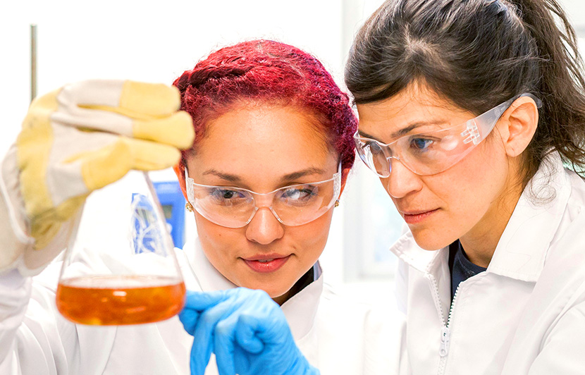 dos estudiantes de ingeniería en nanotecnología aplicando técnicas químicas con matraz