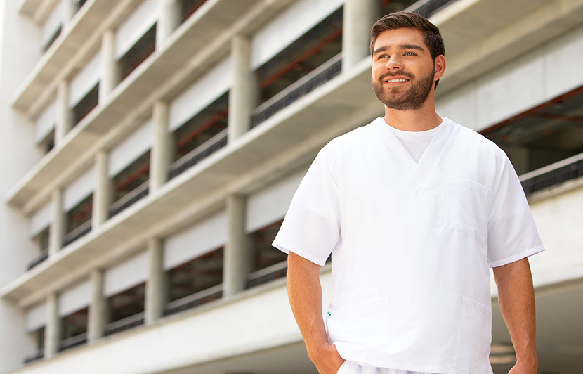 estudiante de medicina con uniforme blanco frente a edificio universitario