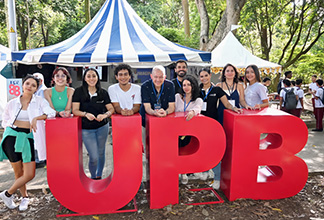 grupo de personas en un evento al aire libre posando sobre grandes letras UPB