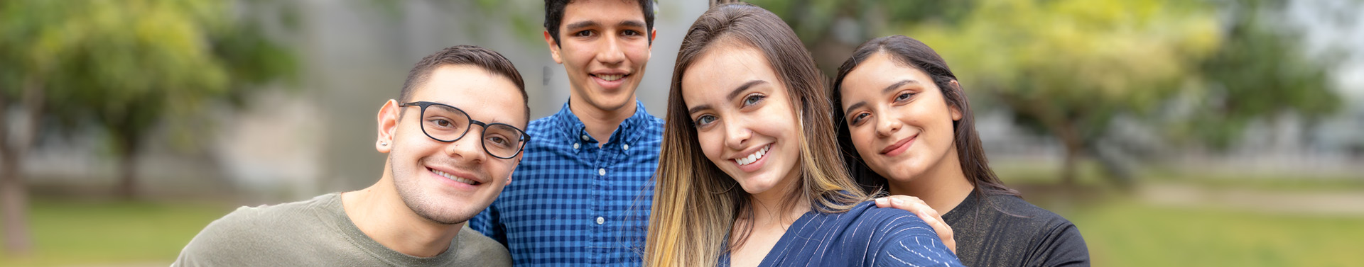 cuatro estudiantes universitarios tomándose una selfie y sonriendo