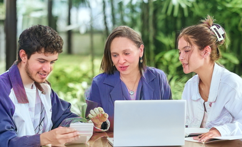 asesor académico orientando a dos estudiantes en los servicios de la universidad