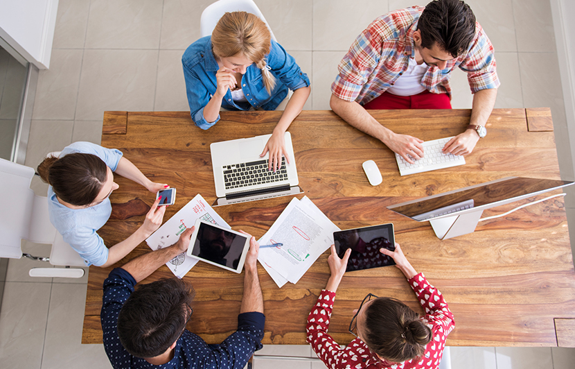 equipo de trabajo en equipo con dispositivos digitales y documentos