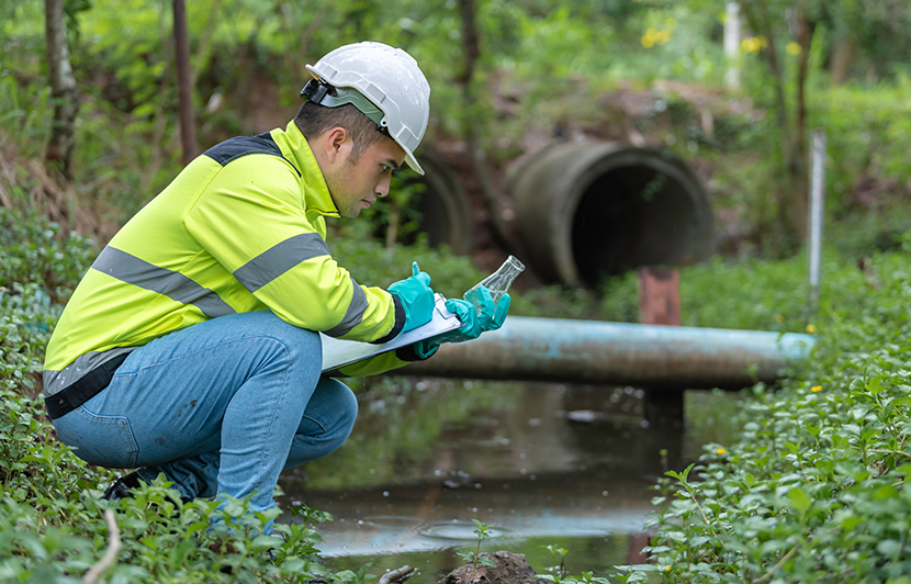 técnico recogiendo muestra de agua en zona natural para análisis ambiental