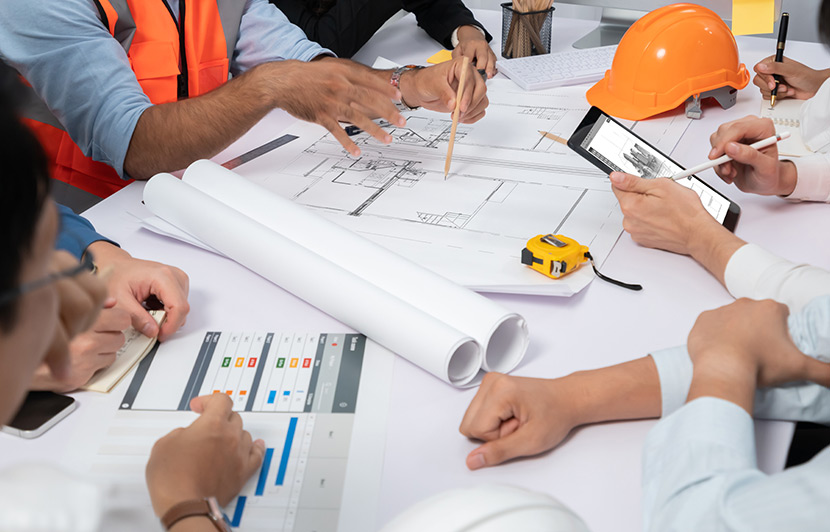 mesa de trabajo con planos, herramientas y dispositivos para planificación de construcción