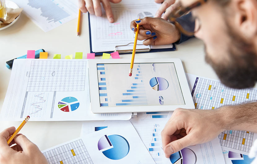 equipo revisando estadísticas y datos de consumidor en documentos y tablet