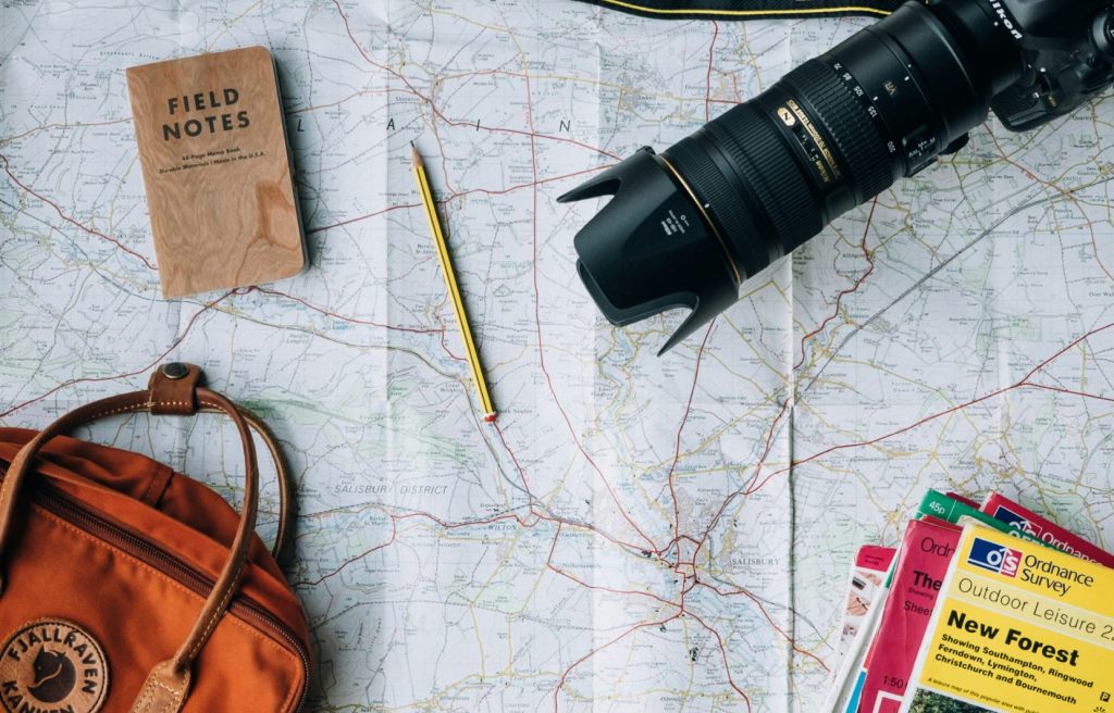 Mapa con brújula, cuaderno y cámara de fotos.